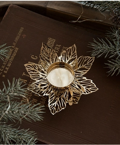 Detail of golden metal leaf candle holder on vintage book with pine needles decoration