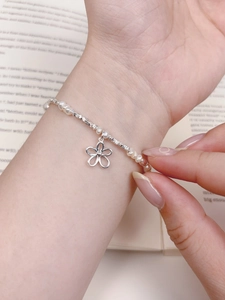 Detail of s925 silver flower charm bracelet with freshwater pearls on a vintage book
