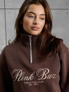Détail d'un sweat à col zippé marron foncé montrant l'imprimé et la texture du tissu