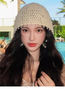 Cappello da sole in maglia beige con nappe di perle indossato da una modella