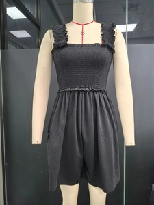 Close-up of black strapless jumpsuit featuring ruched texture and ruffle strap details