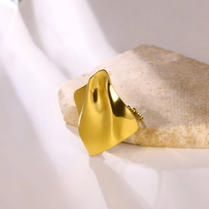 Detailed view of golden irregular wave ring placed on natural stone with woven texture