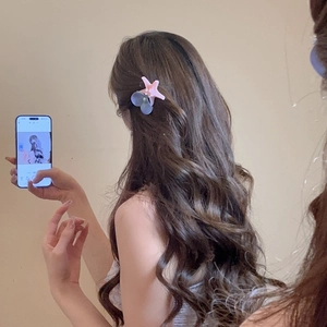 Detail showing acrylic starfish and fabric flower hair clip worn on long wavy hair