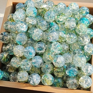 Close-up of crackle glass beads with gold foil in wooden tray for DIY jewelry