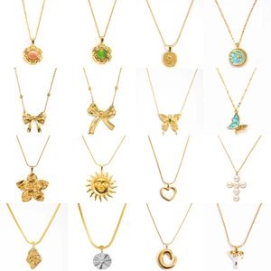 Collection de colliers en acier titane doré avec pendentifs cœur, nœud et croix sur fond blanc