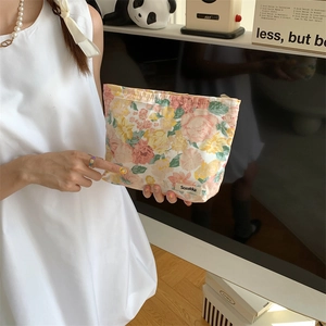 Detail shot of a floral cotton makeup bag with a zipper and side logo tag