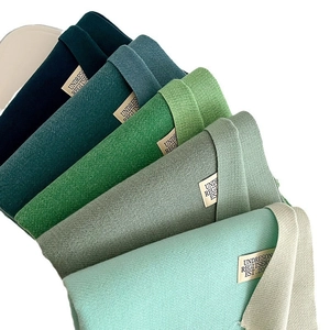 Green gradient cashmere-like scarf with knitted texture and woven labels on white background