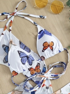 Flat lay of a white bikini top with colorful butterfly prints and halter neck drawstring straps