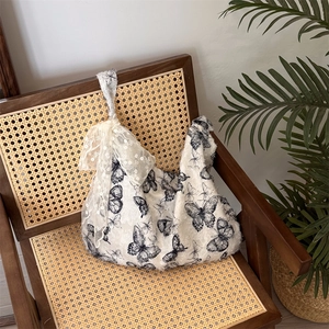 Detail of white tote bag with black butterfly prints and elegant lace ribbon bows