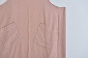 Detailed view of large pockets on a pink linen garden apron with visible yellow stitching