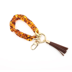 Close-up of amber tortoiseshell acrylic chain with golden clasp and brown leather tassel