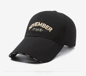 Detail of black baseball cap with khaki November embroidery and Sport text on visor