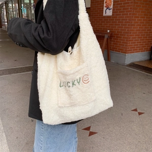 Detailansicht der weißen Fleece-Tasche mit Lucky-Stickerei an einem Modell im Freien