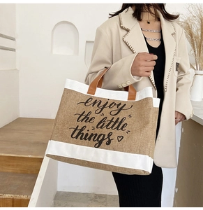 Dettaglio borsa in lino con stampa 'enjoy the little things' e manici in pelle