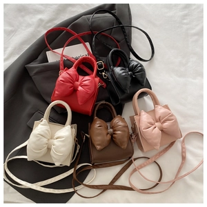 Flat lay of five colorful bow-knot handbags in red black cream brown and pink