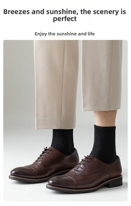 Detail shot of men's dark brown leather cap-toe shoes with black mid-calf knit socks