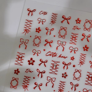 Macro detail of 3D embossed red bow nail stickers with metallic finish and floral patterns