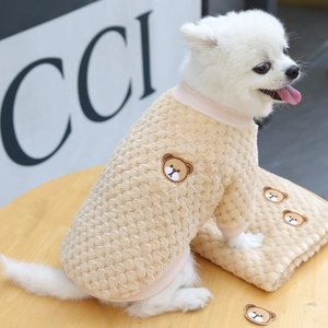 Dettaglio dei polsini a coste rosa e ricamo a orsetto su maglione beige per animali
