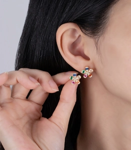 Detailed close-up of rainbow crystal daisy earrings on ear with gold plating