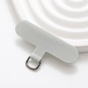 Macro shot of grey fabric phone tether tab with durable metal D-ring on white tray