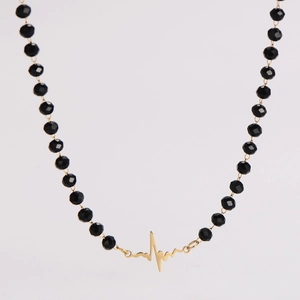 Detailed view of black faceted glass beads with a golden heartbeat pattern pendant