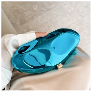 Detail of blue geometric metal clutch bag with mirror finish and golden round clasp