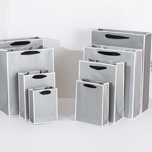 Gray paper shopping bags with white borders and black handles in various sizes