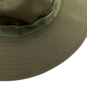 Dettaglio macro del tessuto in nylon ripstop verde oliva con cuciture rinforzate sul cappello