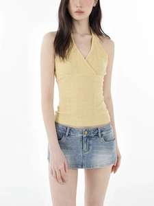 Slim fit yellow knit halter top with V-neck paired with denim skirt on white background