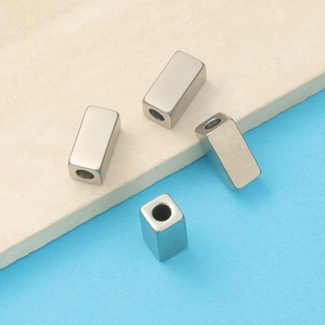 Detailed view of four silver square cuboid beads for jewelry making and DIY crafts