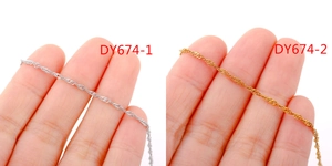 Detail of twisted silver and gold water wave chains held by hand for DIY jewelry
