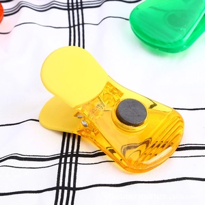 Clip magnetica gialla traslucida per sigillare snack su un panno a quadretti neri e bianchi