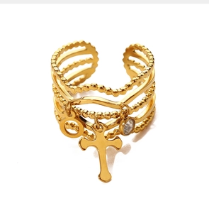 Macro detail of gold-layered cross ring with zircon feminine symbol charms on white background