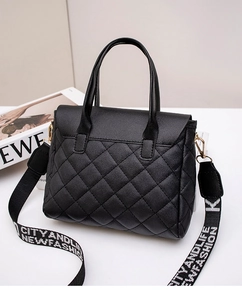 Close-up of black quilted handbag with a wide fashion strap and gold hardware accents