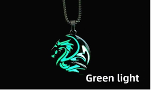 Close-up of a dragon totem pendant glowing green in the dark with black metal base