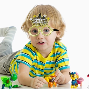Kid wearing gold crown-shaped Happy New Year party glasses with sparkling glitter