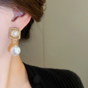 Detail von Vintage-Ohrsteckern mit Doppelperle in Gold-Optik an einem Modell