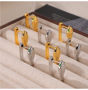 Detailed close-up of snake head huggie earrings with green and black gem eyes in gold and silver