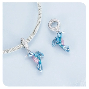 Macro detail of S925 silver hummingbird charm with blue enamel and zircon inlay
