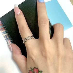 Detailed view of a silver stainless steel chain ring worn on a finger in a lifestyle setting