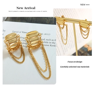 Detailed view of gold chain tassel earrings with rippled geometric texture on a jewelry stand