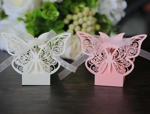 Detail of laser-cut butterfly candy boxes in white and pink with silk ribbon bows