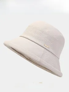 Gros plan du chapeau bob beige montrant la texture du tissu et le badge arth doré