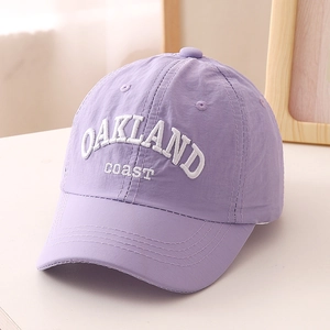 Detail of white OAKLAND embroidery on a lilac quick-dry baseball cap with fabric texture