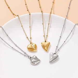 Modische Herzanhänger-Halsketten in Gold und Silber auf einem Keramikteller präsentiert