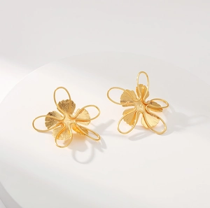 Creative 18K gold plated brass floral stud earrings on a white geometric stand