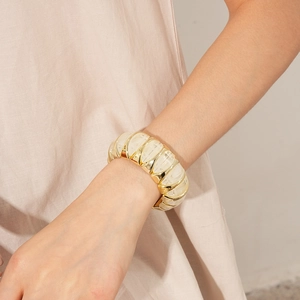 Detailed view of a wide elastic bracelet featuring gold metal and creamy resin rhombic tiles