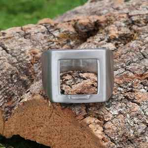 Détail macro d'une bague décapsuleur large en acier inoxydable sur fond en bois