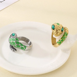 Detail of snake rings with green gem eyes and scale texture on a ceramic tray