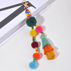 Dettaglio portachiavi con pompon colorati, perline in legno e nappe a strati vivaci